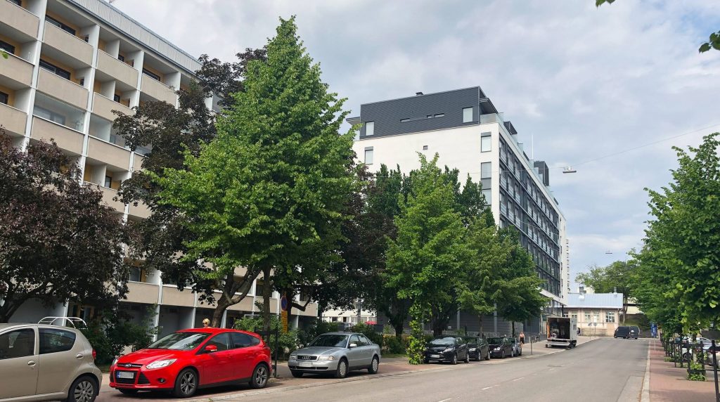 Newly built and 1970s' apartment buildings on Vähä-Hämeenkatu in the Eastern Center of Turku. Old trees add lushness to the area.