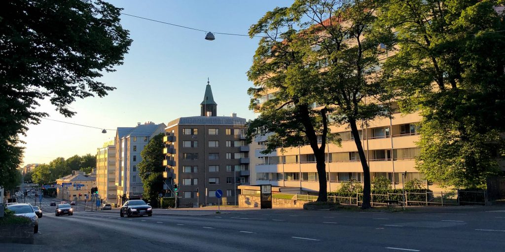 Turun Itäinen keskusta Uudenmaankadun varrella ja alueelle tyypillisiä 1970-luvun kerrostaloja ilta-auringossa. Taustalla Turun Tuomiokirkko.
