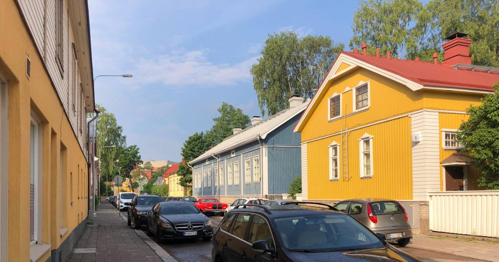 Yellow and blue wooden houses in Pohjola neighborhood in Turku basking in the sunlight on a bright summer day.