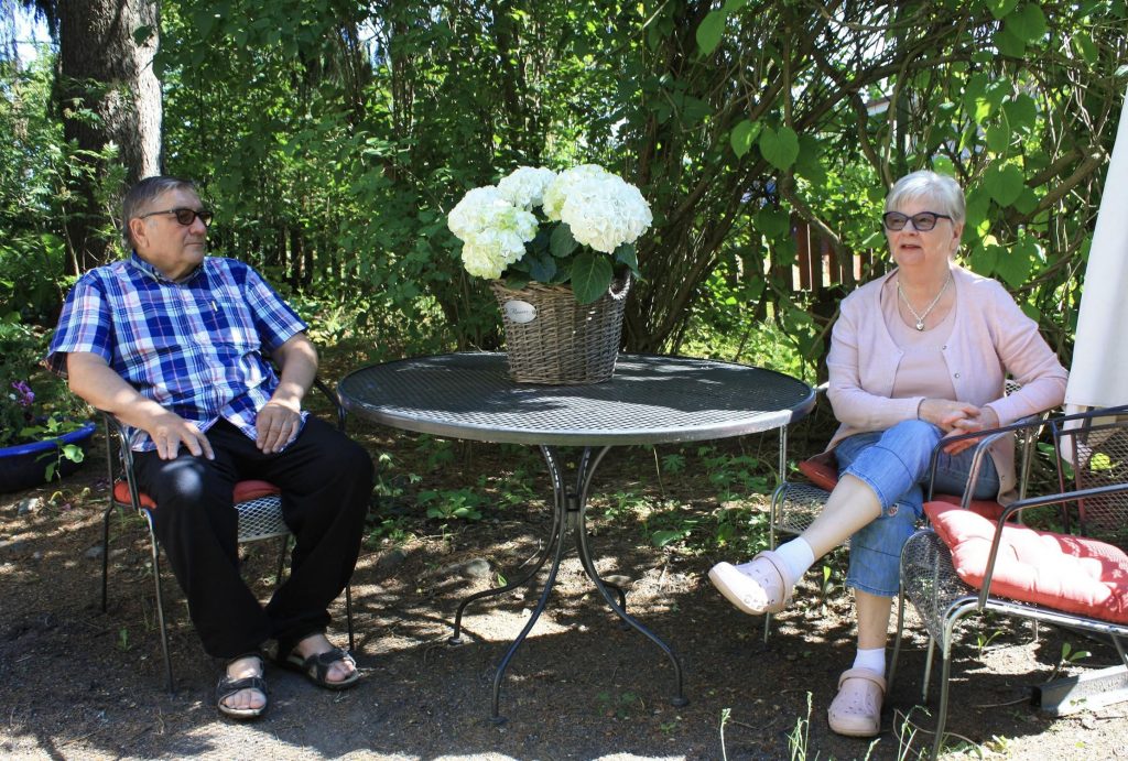 Kari ja Tuire istuvat omassa rehevässä puutarhassaan.