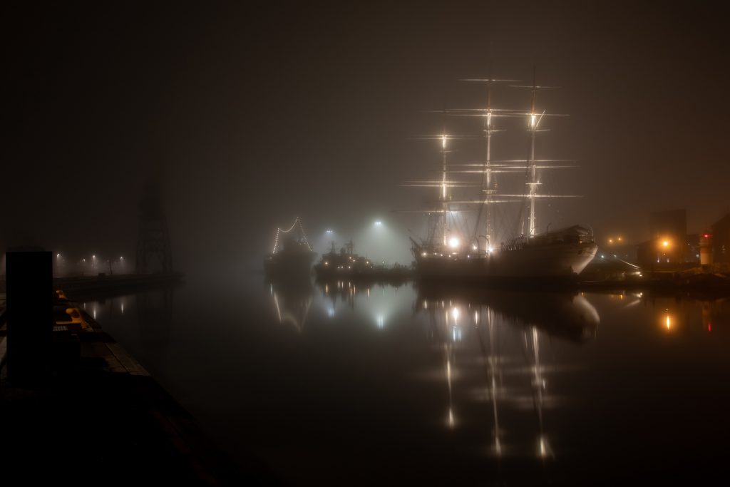 The lights of the sail ship Suomen Joutsen on a dark foggy night in the Aura River.