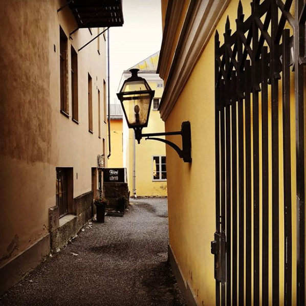 Old narrow street with a street lamp on a building wall and a opened black gate in old Turku in the environment of the Old Market Square. 