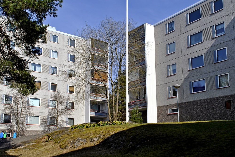 Turun Varissuon naapurustossa kaksi harmaata kerrostaloa ja niiden keskellä keväinen kallioinen piha ja muutama lapsi. 