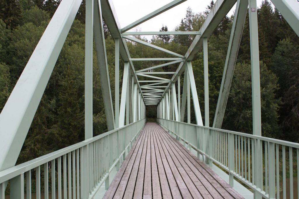 Maarian altaan ylittävä silta, jossa on puinen lattia ja vihreät metalliset kaiteet sivuilla ja yläpuolella.