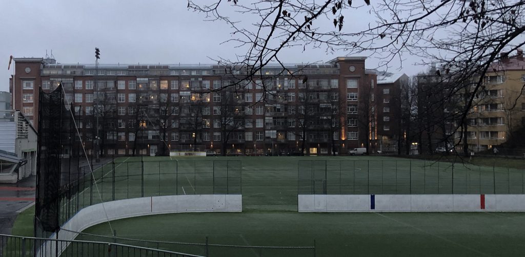 Turun Verkahovin punatiilinen kerrostalo taustalla ja Parkin jalkapallokenttä etualalla marraskuisena, sateisena päivänä.