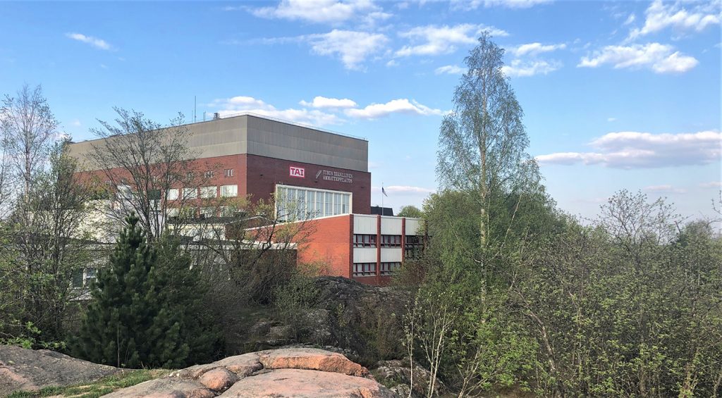 Suuri, kuution muotoinen ja punaisella tiilellä verhoiltu koulurakennus kallioisen Juhannuskukkulan päällä Pohjolan asuinalueella Turussa. 