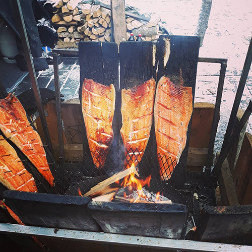 Salmon is being smoked on an open fire.