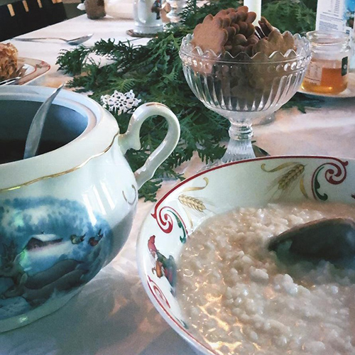 Jouluinen aamiainen, jossa on tarjolla kulhoissa riisipuuroa, rusinakeittoa ja pipareita. Koristeluna havunoksia pöydällä.