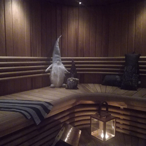 Sauna with two grey-colored christmas gnomes, two sauna pillows and a lantern.