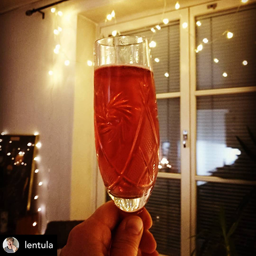 Red drink in a crystal classa, Christmas lights in the background.