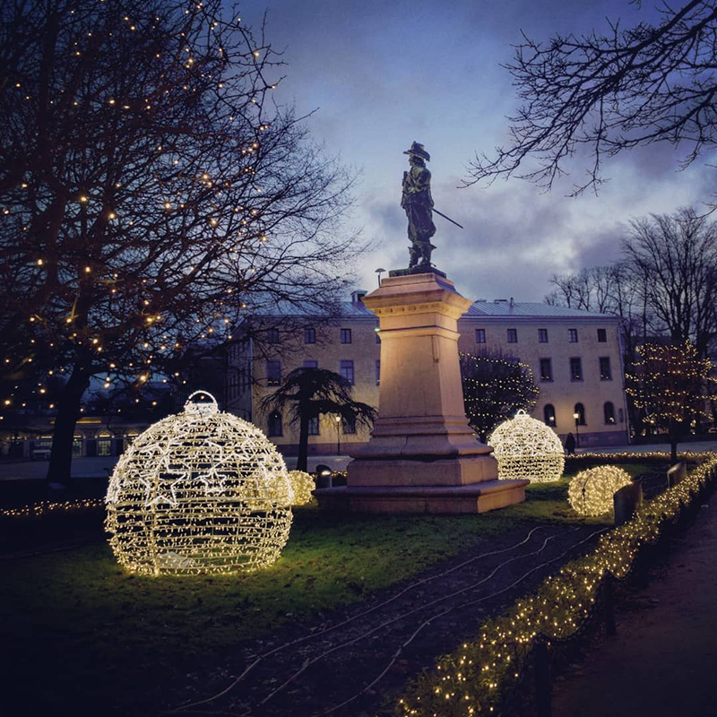 Big ball shaped Christmas decoration lights under the statue of Pietari Brahe in Brahe Park in Eastern Center of Turku.