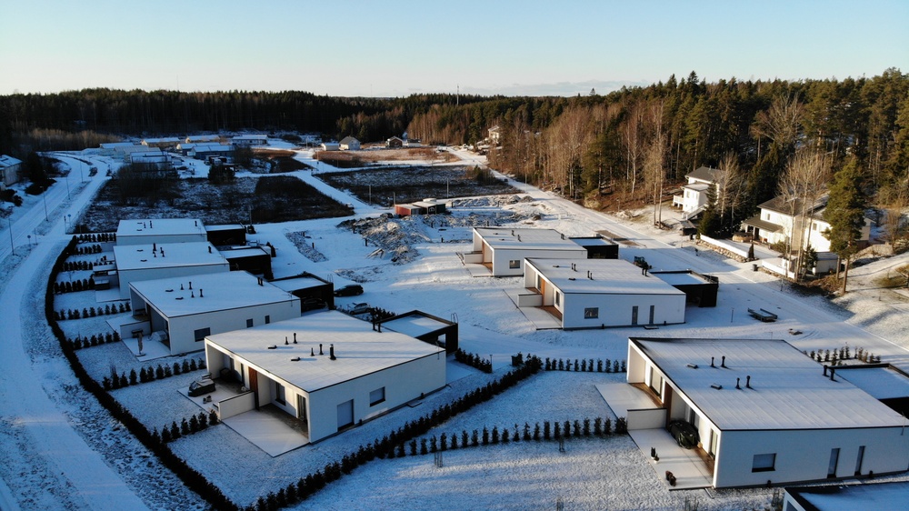 Ilmakuva Kuusiston asuinalueen Empon lounaisosista, jossa on moderneja neliskulmaisia valkoisia paritaloja talvella.