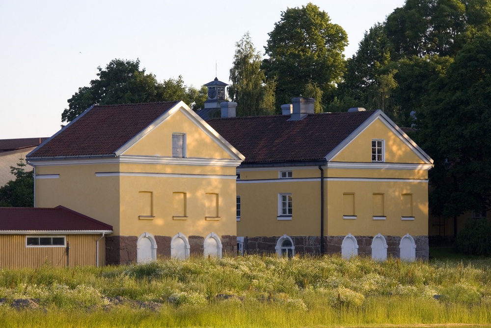 Tuorlan majatalon historialliset keltaiset kivirakennukset aurinkoisena kesäpäivänä.