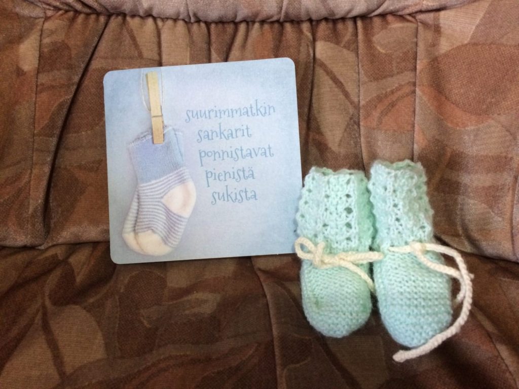 Small baby shoes knitted by a neighbor and a greeting card.