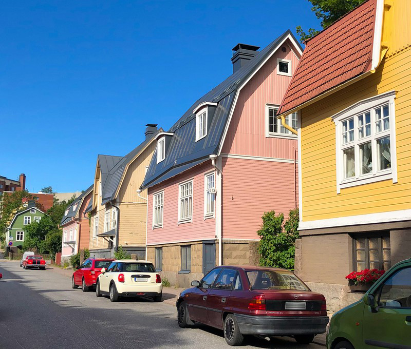 Many wooden houses with different colors by a street in the neighbourhood of Pohjola in Turku.
