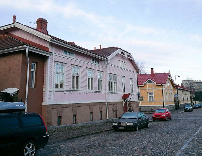 One pink wooden house and one yellow wooden house by a street in the neighbourhood of Port Arthur in Turku.