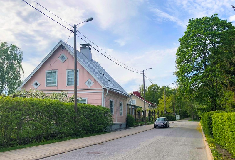 Light pink wooden detached house by an asphalt road in the neighbourhood of Vasaramäki in Turku.