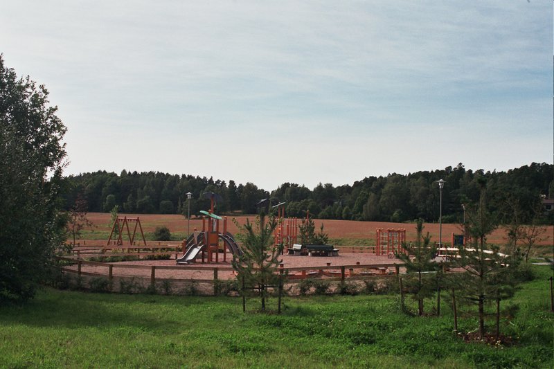 Turun Härkämäen leikkipuisto ja sen ympärillä matala aita, nurmikkoa, peltoa ja metsää.