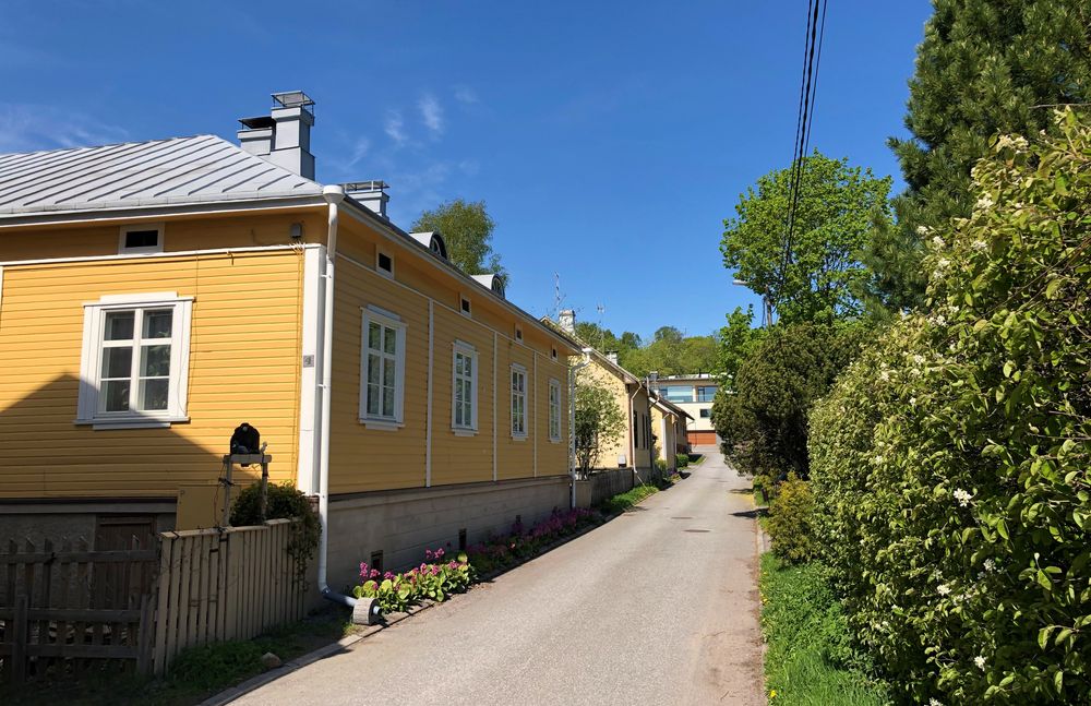 Yellow row house by a small road and greenery in the neighbourhood of Vätti.