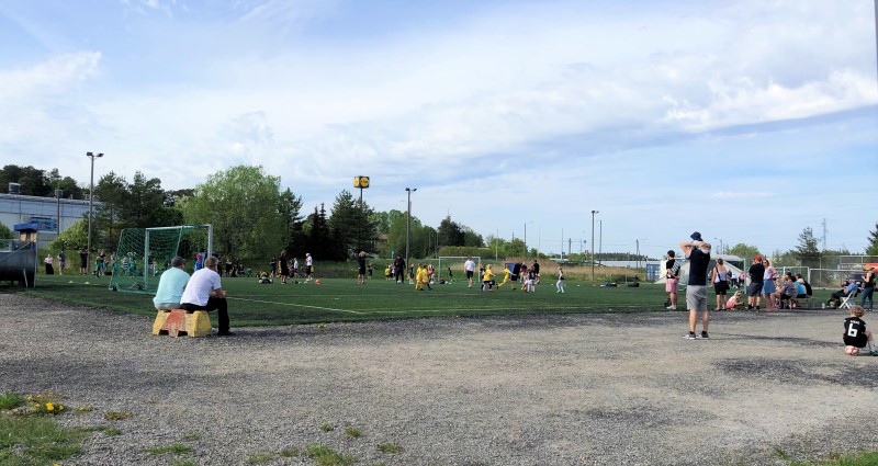 Lapset pelaavat jalkapalloa Turun Huhkolan nurmikentällä.