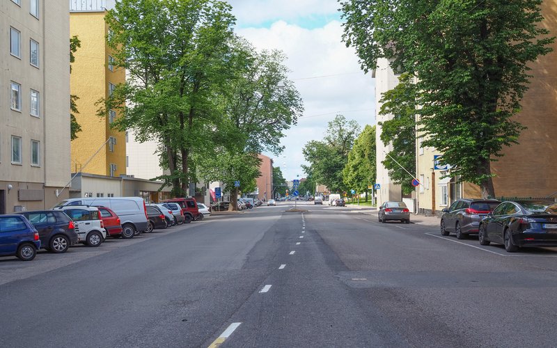 In the middle is the Itäinen Pitkäkatu in the eastern center of Turku, with colorful buildings and parked cars on both sides.