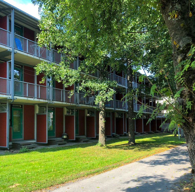 Red colored apartment building and lush trees in Student Village, Turku
