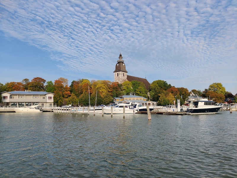 Naantali Church pictured from the sea and boats in front of it in the harbor.