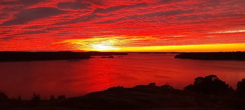 Auringonlasku värjää taivaanrannan ja meren kirkkaan punaiseksi.