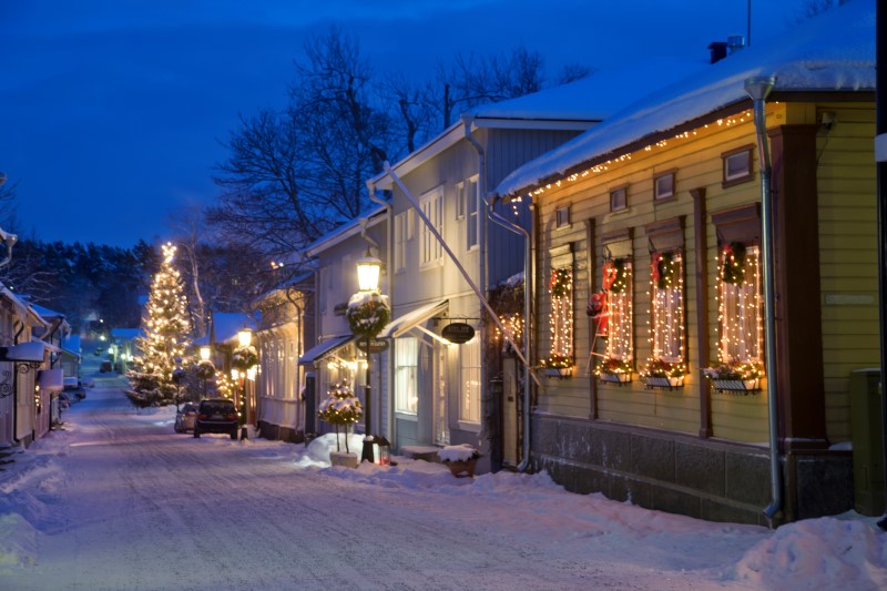 The wooden houses of Naantali old town have Christmas decorations on them on a snowy day.