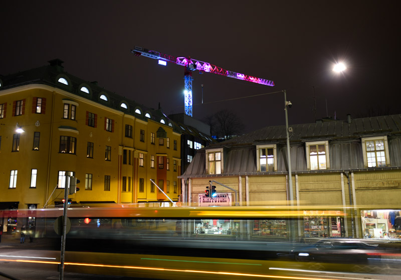 Näyttävästi valaistu nostokurki Turun keskustassa, etualalla vanhoja rakennuksia.