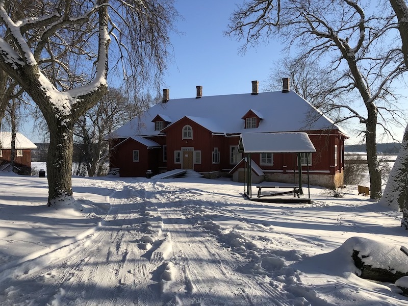 Punainen puinen kartano lumisen maiseman keskellä Kaarinan Kuusistossa.