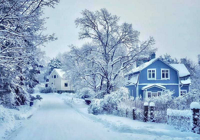 Sininen ja valkoinen puutalo lumisessa maisemassa Turun Itäharjulla.
