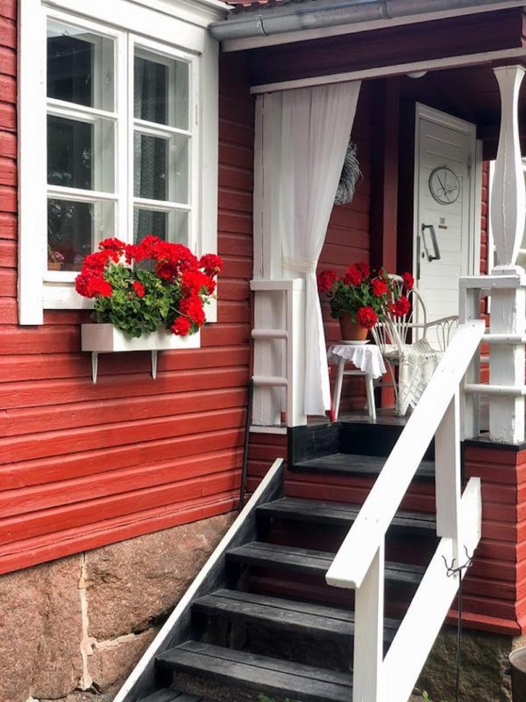 Punaisen puutalon portaat ja kukkaistutukset.