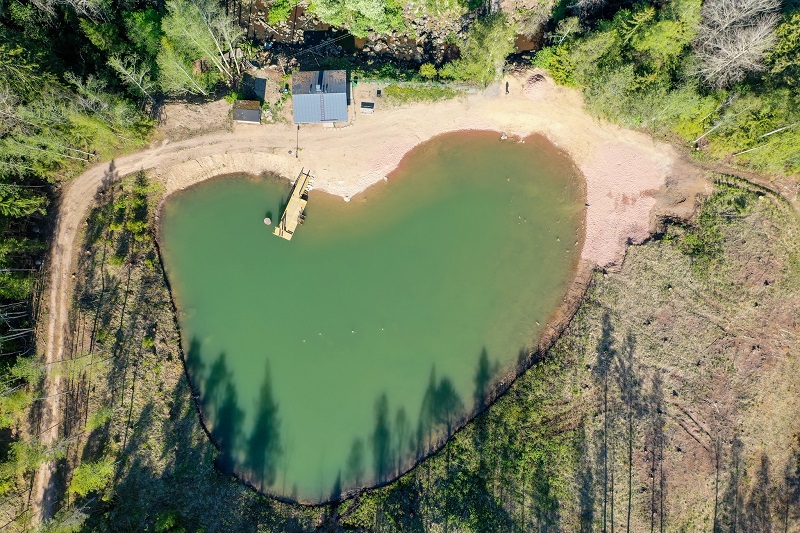 Ilmasta kuvattu sydämen muotoinen järvi, jossa on laituri.