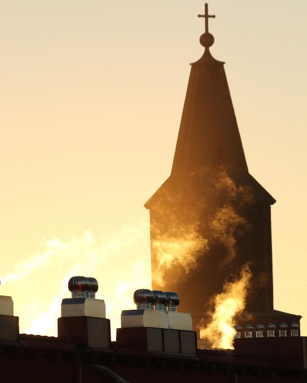 Smoke rising from chimneys against the silhoutte of the tower of Turku cathedral