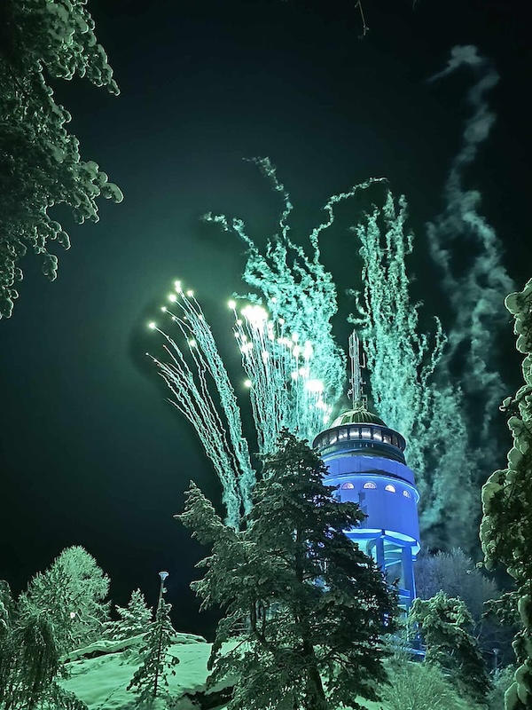 Fireworks in the background of an illuminated tower on a winter night. 
